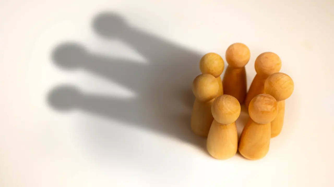 Image of board game pieces standing in a group, throwing a shadow like a crown